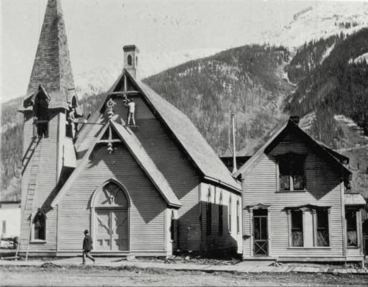 Two men work on the First Congregational Church as a pedestrian strolls by, probably around 1930. Photo courtesy of San Juan County Historical Society